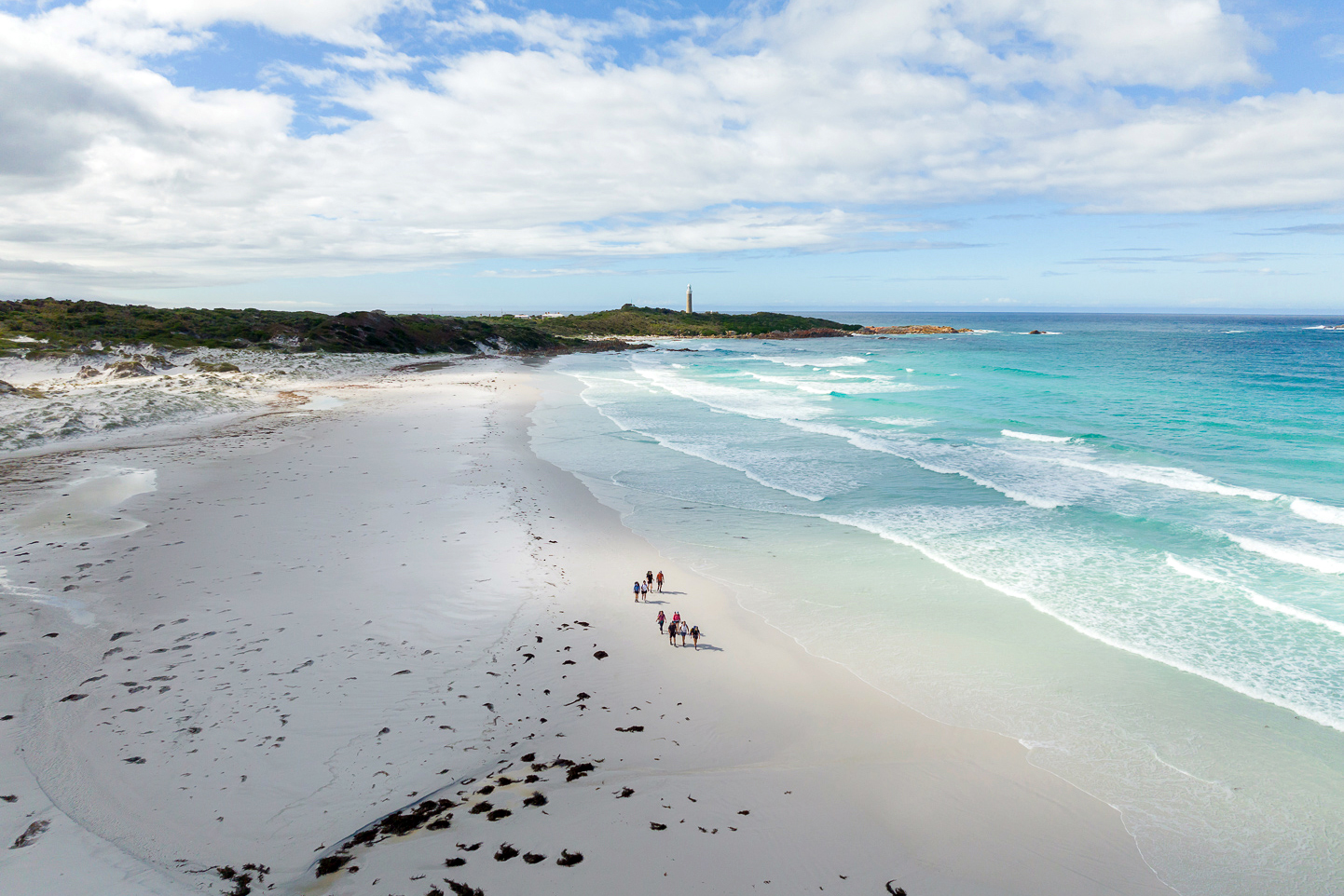 Bay of Fires Best Australian Beach 2025 – walkers on the beach with Eddystone Point Lighthouse in Tasmania